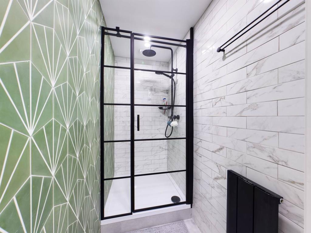 Premium walk-in shower with green geometric feature wall and matte black Crittall frame